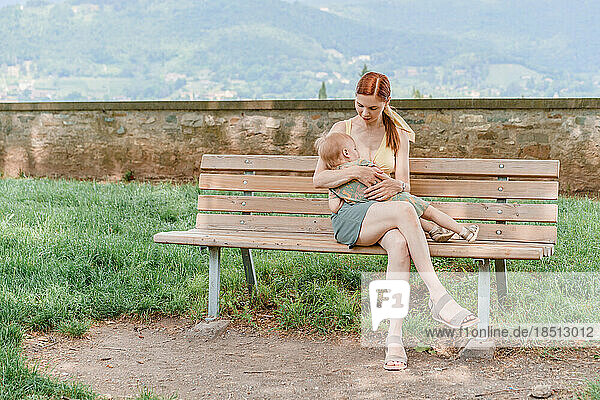 Caucasian woman breastfeeding her baby girl in a park