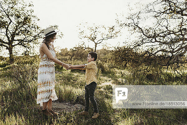Young mother and son holding hands and playing in california field