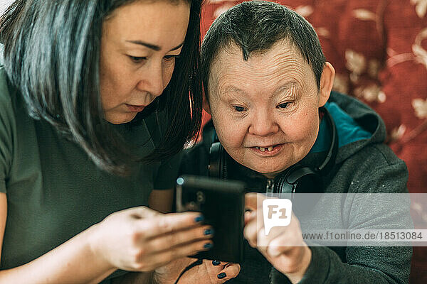 elderly woman with Down syndrome  asian assistant helps to use phone