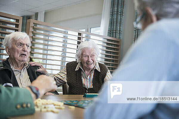 Senior inhabitants having fun playing board game in rest home