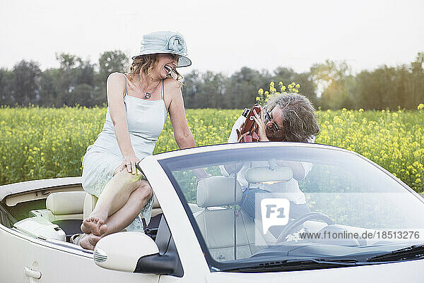 Man photographing happy woman in a car Beetle Cabrio with old school vintage camera  Bavaria  Germany