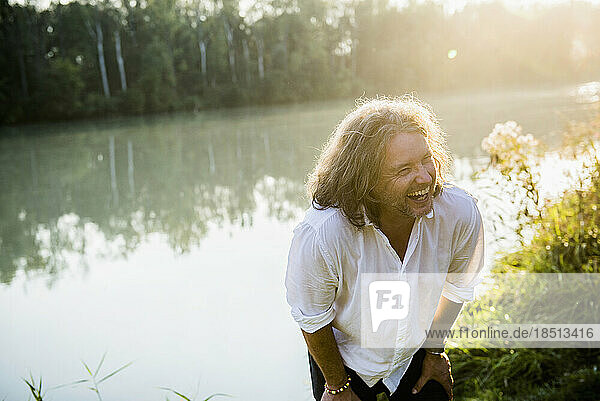Cheerful man in long hair laughing by river  Bavaria  Germany