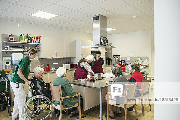 Nurse preparing food with senior inhabitants in rest home