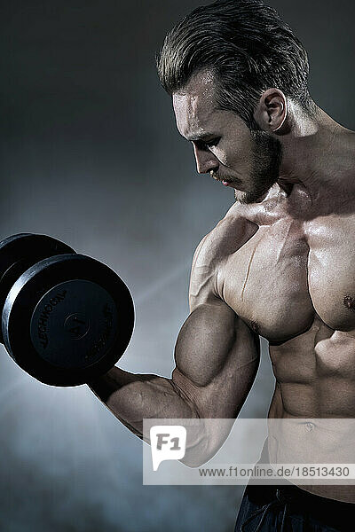 Muscular man doing exercise with dumbbells