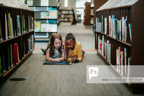 young girls laying on floor reading a picture book