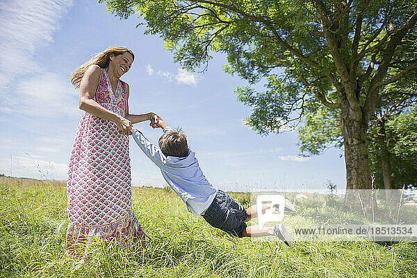Woman swinging boy on meadow in picnic  Bavaria  Germany