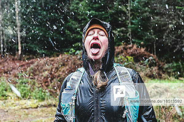 Woman with mouth open catching snow flakes on tongue
