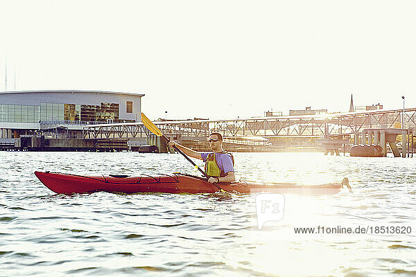 Man on kayak tour paddles though Casco Bay at sunset in Portland Maine