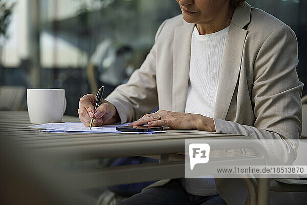 Businesswoman doing paperwork at sidewalk cafe