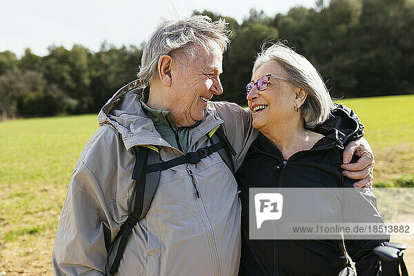 Affectionate senior couple standing in nature with arm around