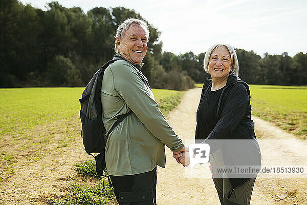 Happy hiking senior couple holding hands in nature