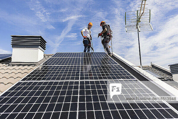 Techniker installieren an einem sonnigen Tag ein Solarpanel unter dem Himmel