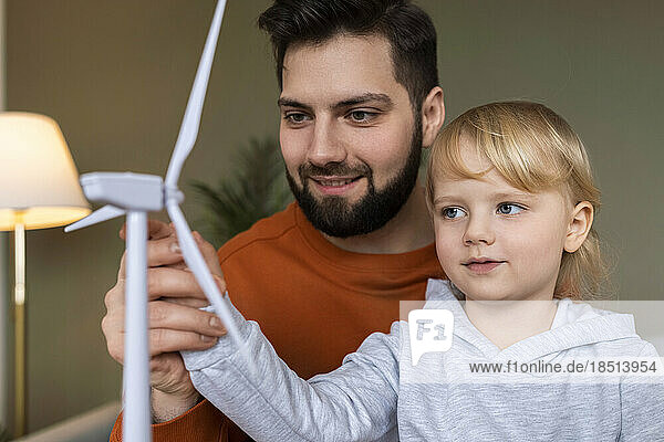 Lächelnder Vater unterrichtet Sohn zu Hause über Windkraftanlagen
