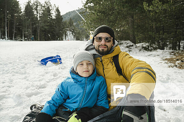 Vater und Sohn sitzen im Schnee