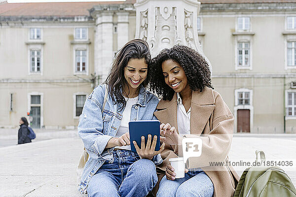Smiling young friends using tablet PC