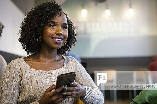Contemplative woman holding smart phone