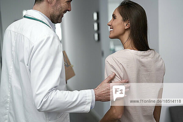 Happy doctor talking with patient in clinic