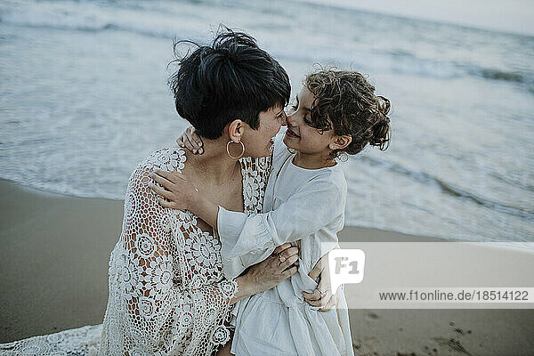 Glückliche Frau umarmt Tochter am Strand