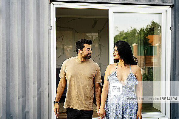 Romantisches Paar hält Händchen vor Containerhaus