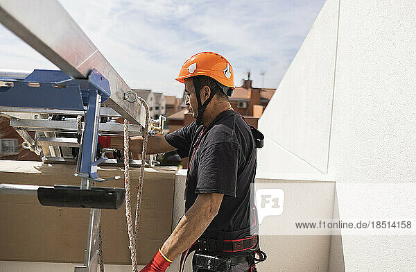 Ingenieur mit Schutzhelm steht an einem sonnigen Tag an der Leiter