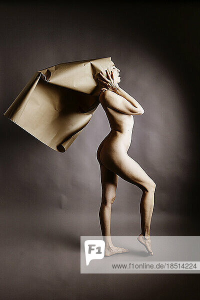 Naked woman holding brown paper on head