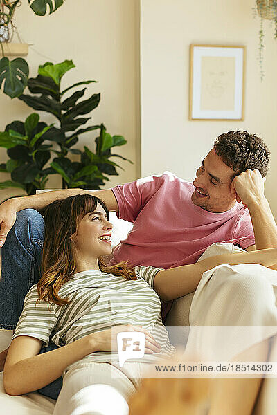 Happy woman lying on girlfriend's lap at home