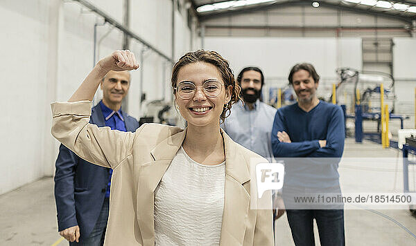 Happy businesswoman flexing muscles standing in front of colleagues
