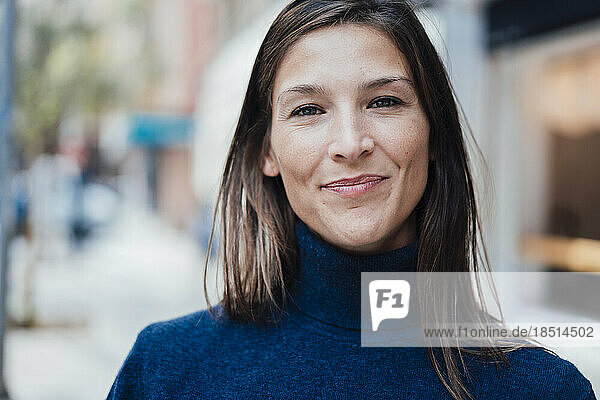 Smiling woman with brown hair wearing blue turtleneck