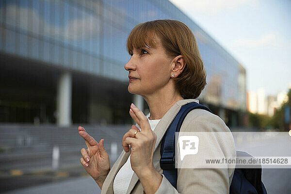 Thoughtful businesswoman with crossed fingers