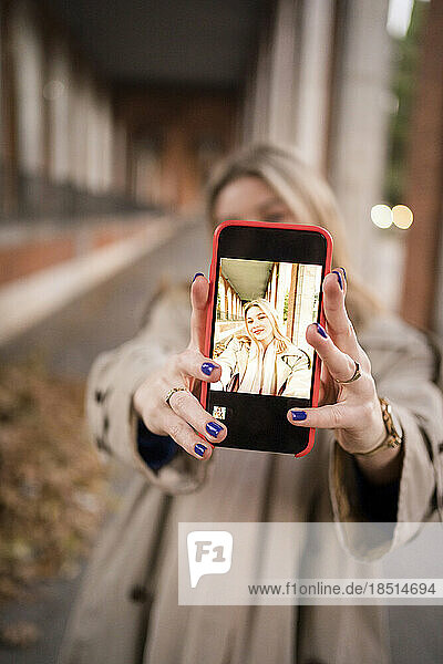 Woman taking selfie through smart phone screen