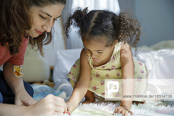 Mother helping daughter to make drawing at home