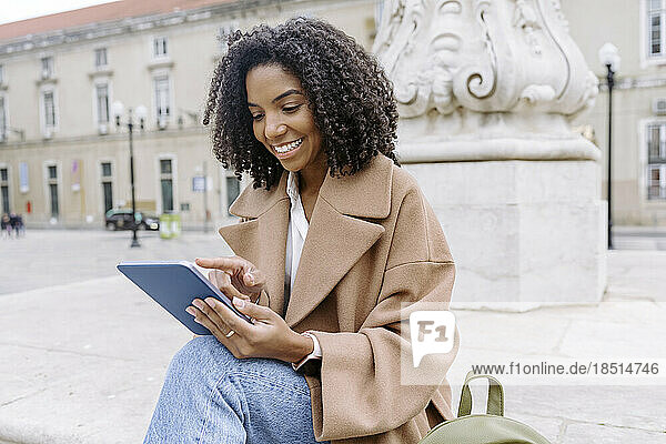 Lächelnde junge Frau benutzt Tablet-PC am Stadtplatz