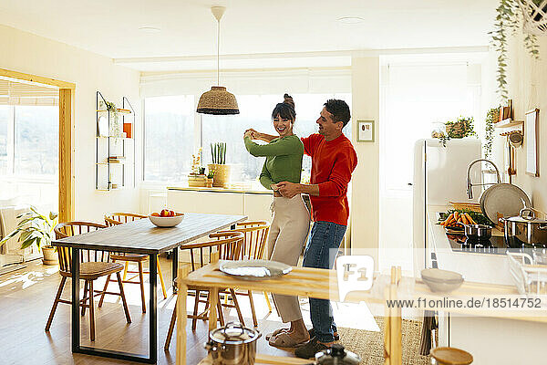Happy couple having fun dancing in kitchen at home