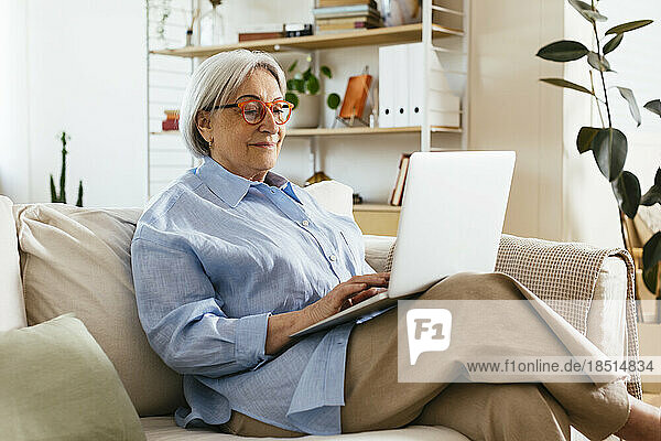 Ältere Frau mit Brille und Laptop zu Hause