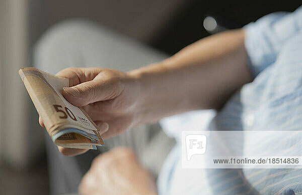 Hands of senior man with European paper Currency