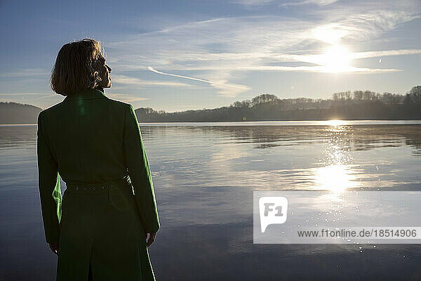 Thoughtful woman looking at lake on sunny day