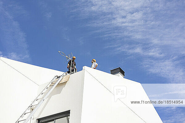 Technician standing on roof under sky