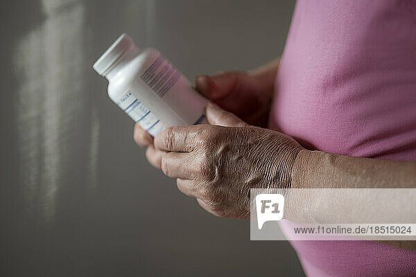 Senior man holding bottle of vitamins and probiotics