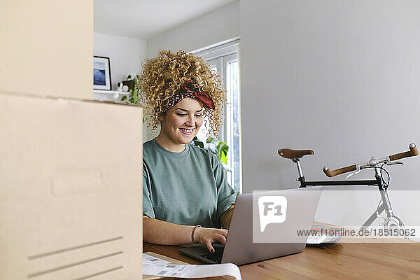 Glückliche junge Geschäftsfrau  die am Schreibtisch am Laptop arbeitet
