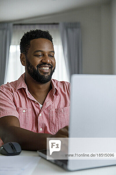 Happy freelancer working on laptop at desk in home