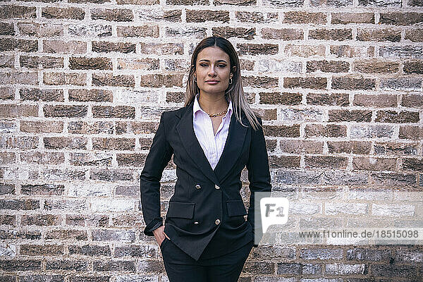 Confident businesswoman standing in front of brick wall