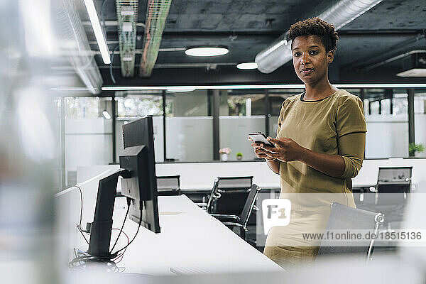 Businesswoman standing with mobile phone in office
