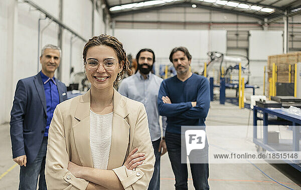 Happy engineer standing with arms crossed in front of colleagues