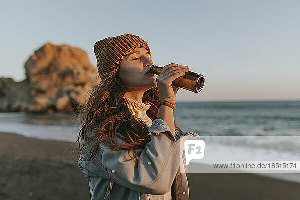 Woman drinking beer at beach