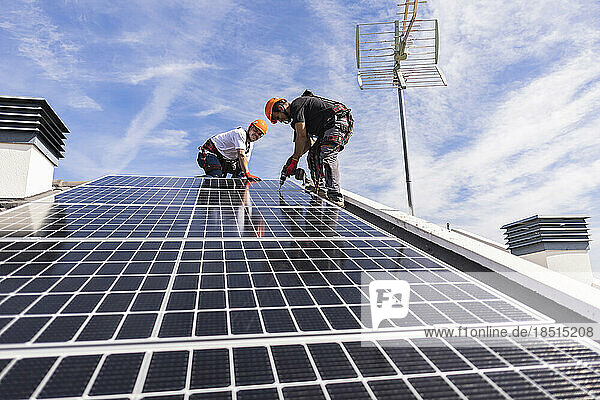 Ingenieure installieren an einem sonnigen Tag ein Solarpanel unter dem Himmel