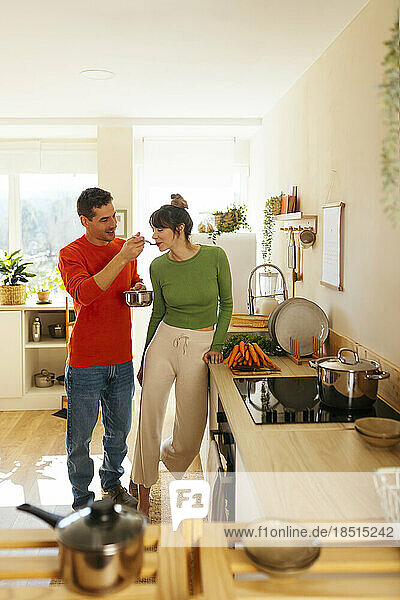 Man feeding woman by kitchen counter at home