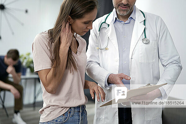 Mature doctor discussing over document with patient