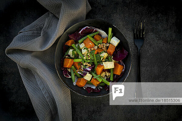 Bowl of ready-to-eat vegetarian salad with sweet potato  celery  radicchio  green beans  croutons  walnuts and parsley