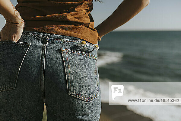 Flowers in back pocket of jeans worn by woman at beach