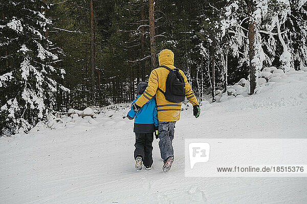Father walking with arm around son in snow